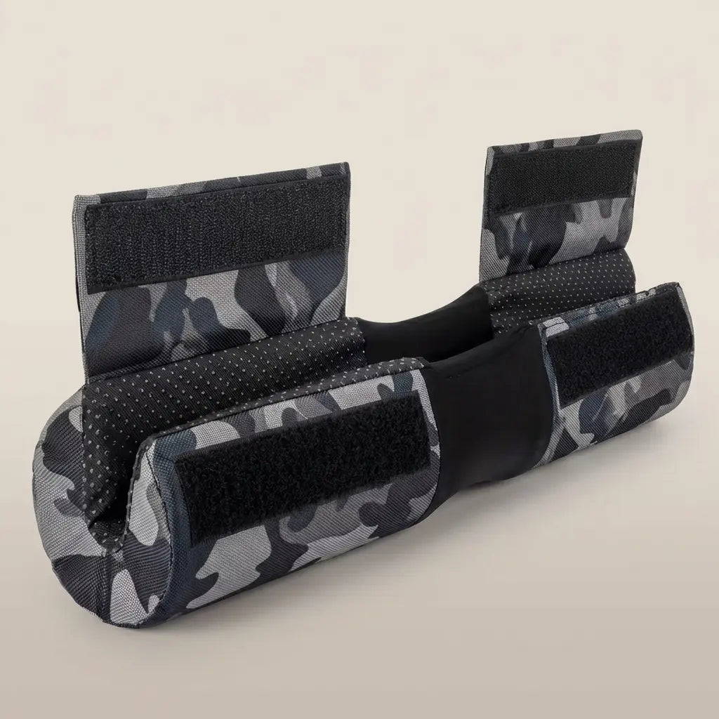 Celvian barbell pad in obsidian camo with ergonomic neck cutout, cushioned support, and hook-and-loop straps, shown in angled studio product view.
