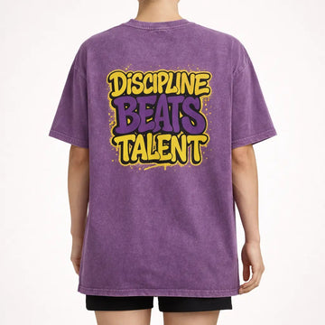 Back view of purple acid-wash oversized t-shirt with large ‘Discipline Beats Talent’ graphic print.