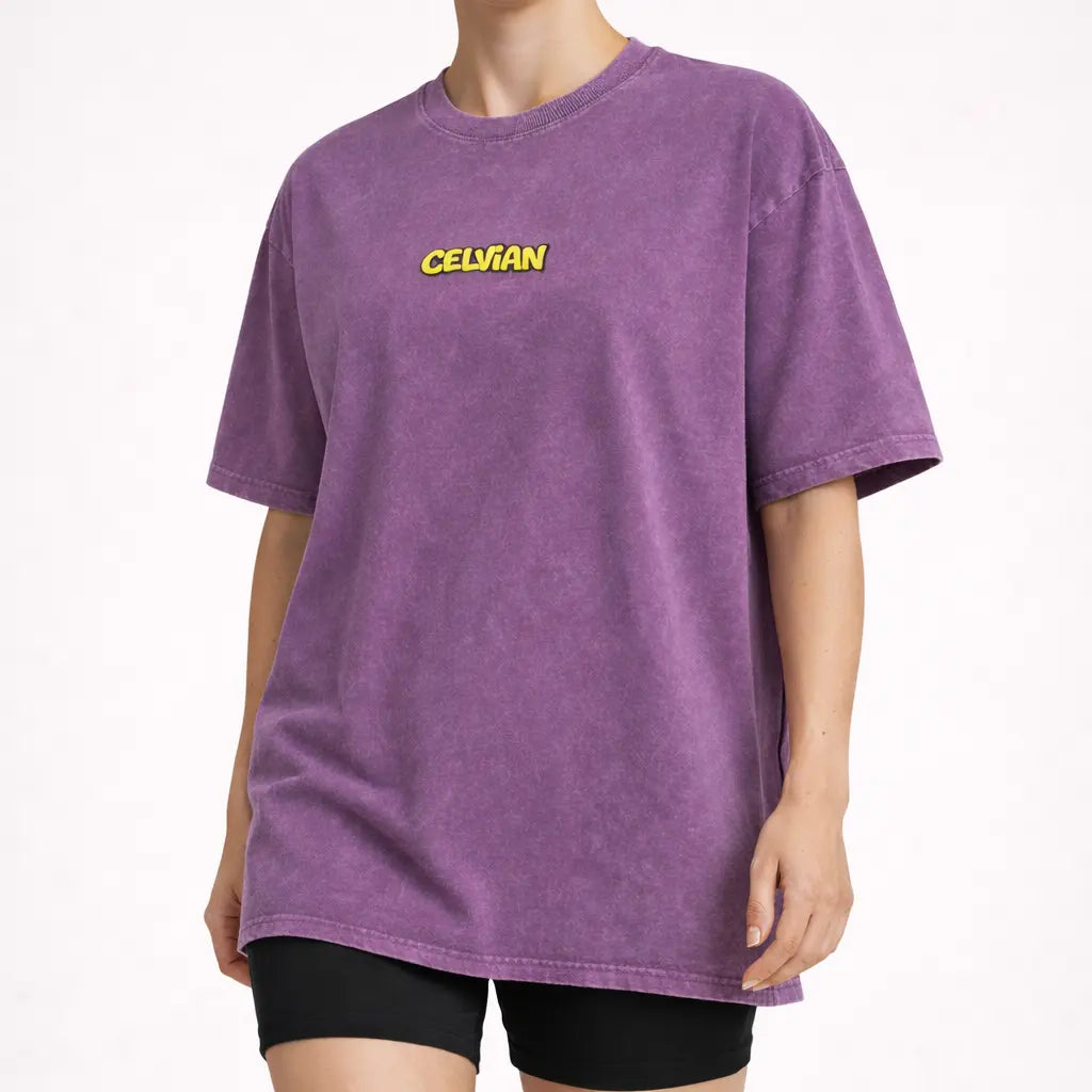 Angled front view of purple washed oversized t-shirt with small yellow Celvian logo on chest.