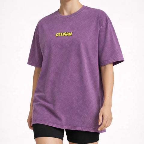 Angled front view of purple washed oversized t-shirt with small yellow Celvian logo on chest.