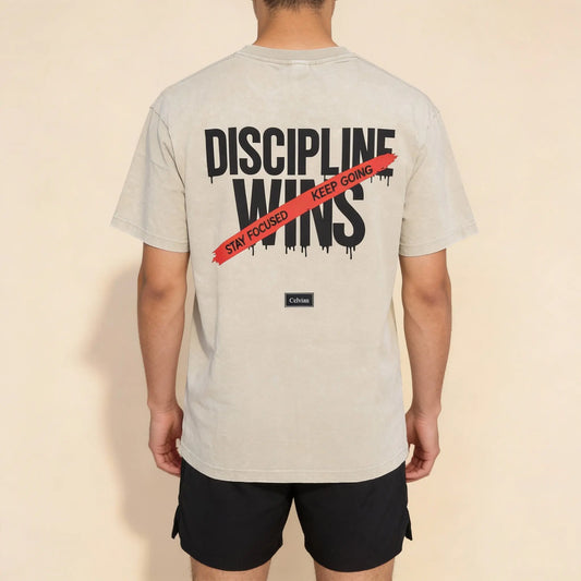 Back view of beige oversized t-shirt with ‘Discipline Wins’ print and red ‘Stay focused, keep going’ stripe, Celvian label. 2048