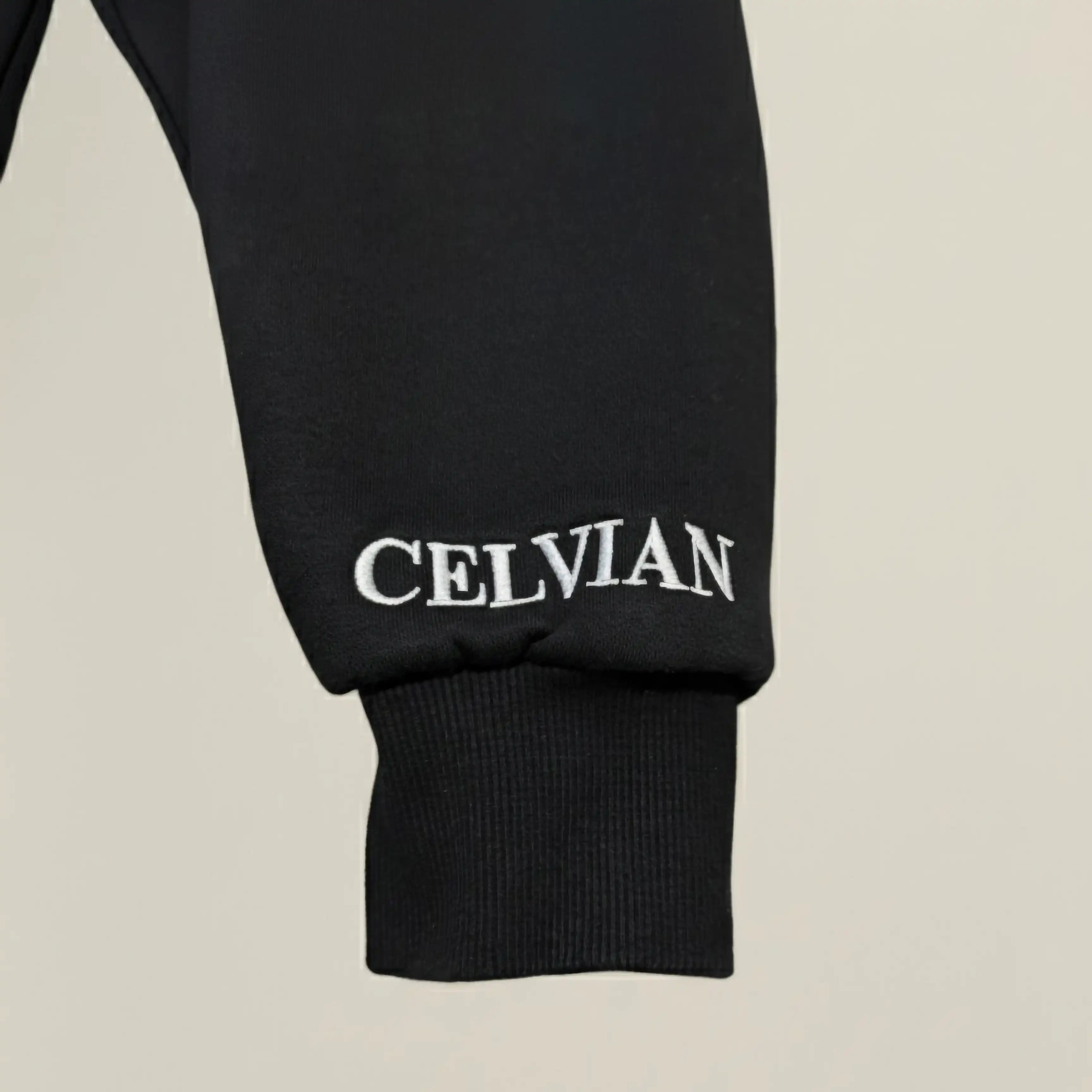 Black hoodie sleeve with 'CELVIAN' branding on a beige background