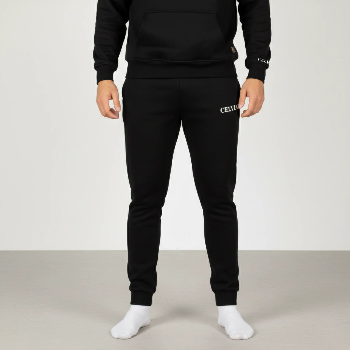 Celvian Distinctive black pants, front view highlighting embroidered logo on thigh, tapered fit with cuffed ankles, studio shot.