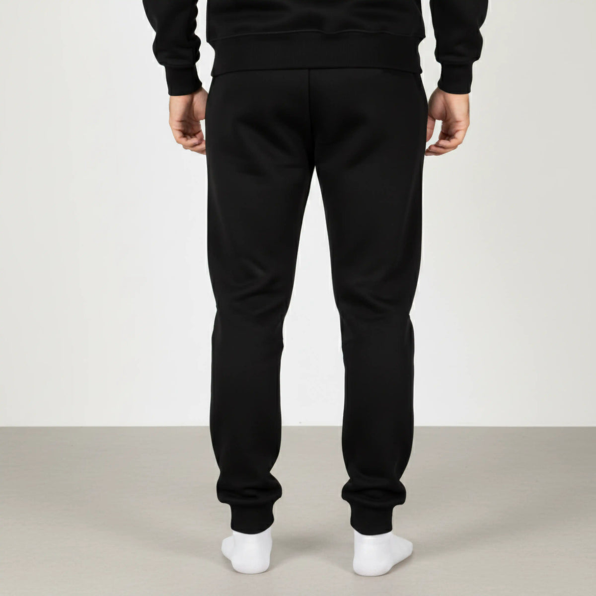 Celvian Distinctive black pants, back view showing tapered fit and cuffed ankles, minimalist design, studio lighting.