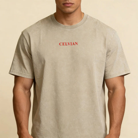 Close-up front view of the Celvian Stay Driven T-Shirt in washed beige, featuring a small red CELVIAN chest logo, oversized fit, and clean minimal design.