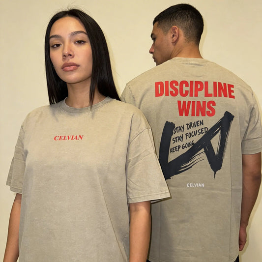 Front and back view of the Celvian Stay Driven T-Shirt in washed beige, shown on two models with a small red CELVIAN chest logo on the front and a bold red ‘DISCIPLINE WINS’ graphic with dark brushstroke artwork on the back. 2048